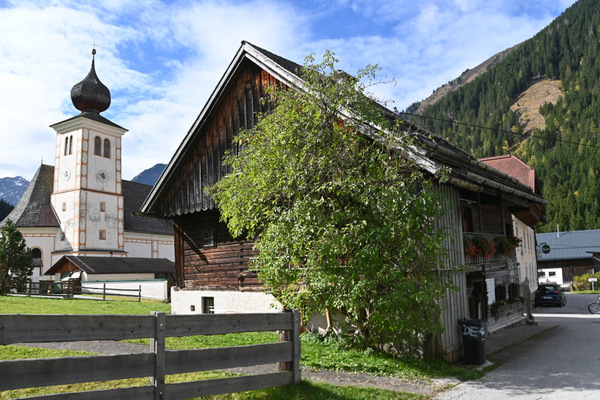 Ansicht von außen auf das Mesnerhaus, daneben die Kirche